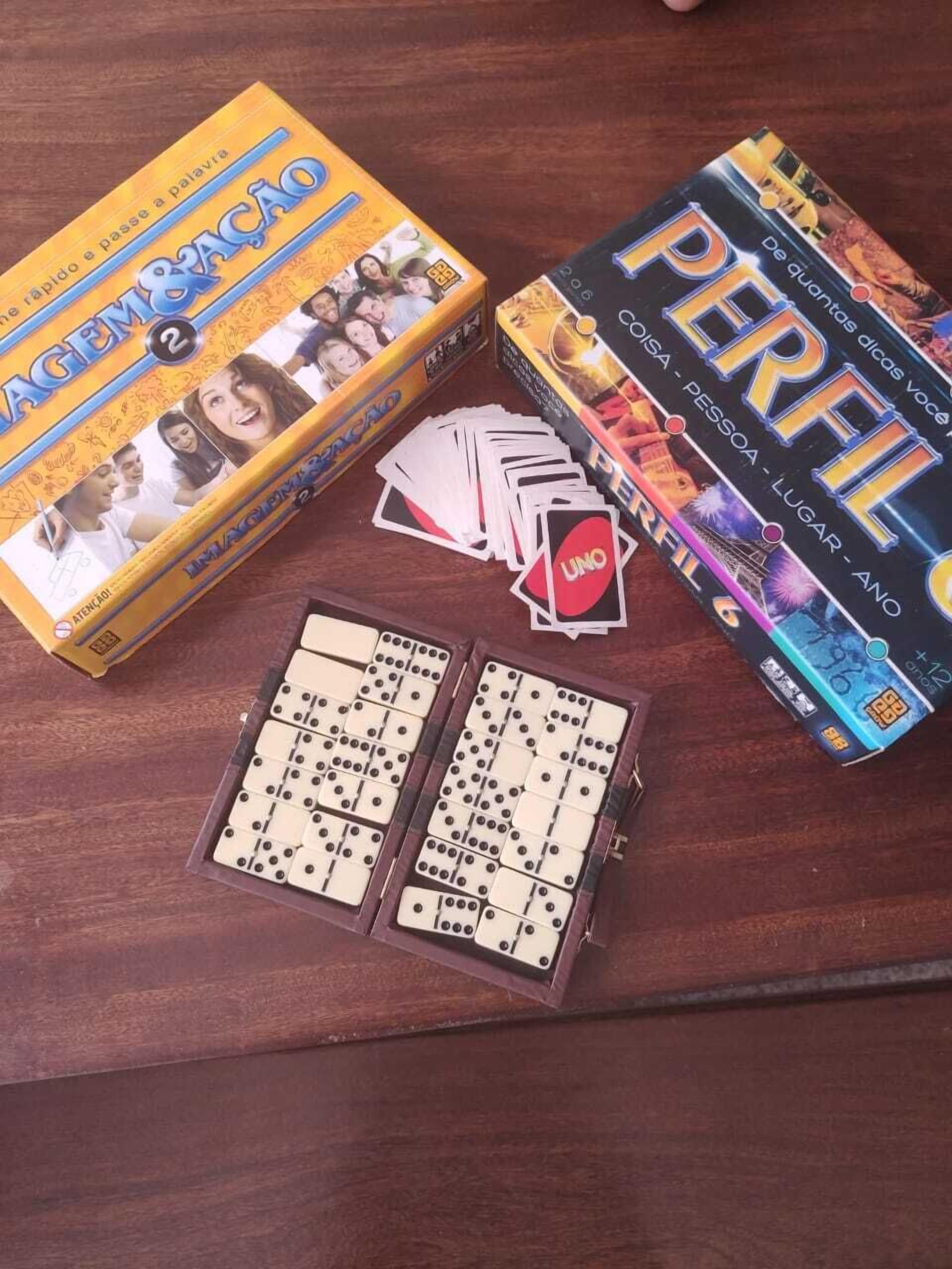 A wooden table with two board games, one with a yellow box and one with a blue box, and a set of dominoes.