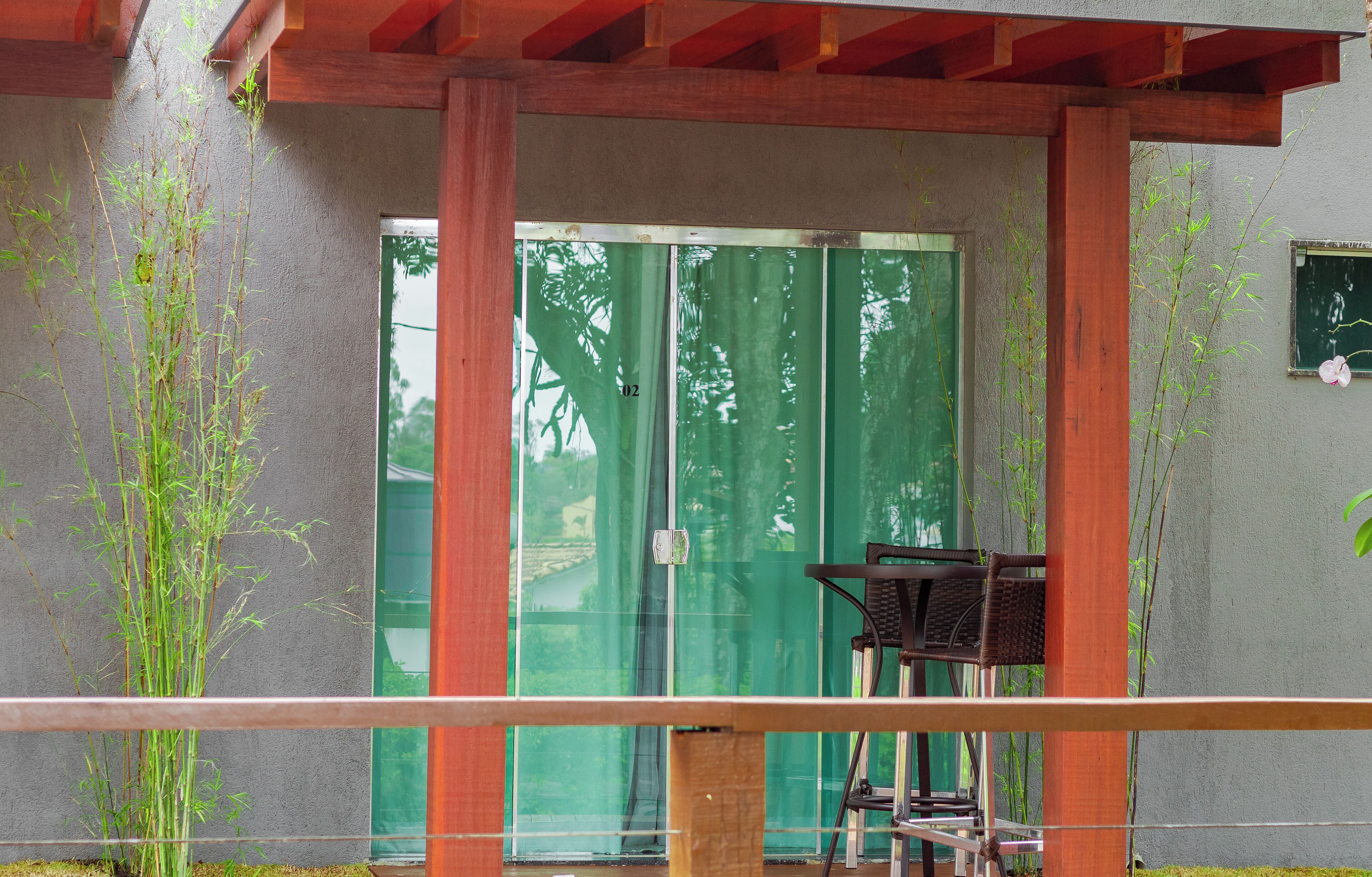 A covered outdoor area with a table and chairs, a green sliding door, and bamboo plants.