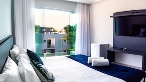 Habitación de hotel con cama, televisión y vista a edificios.