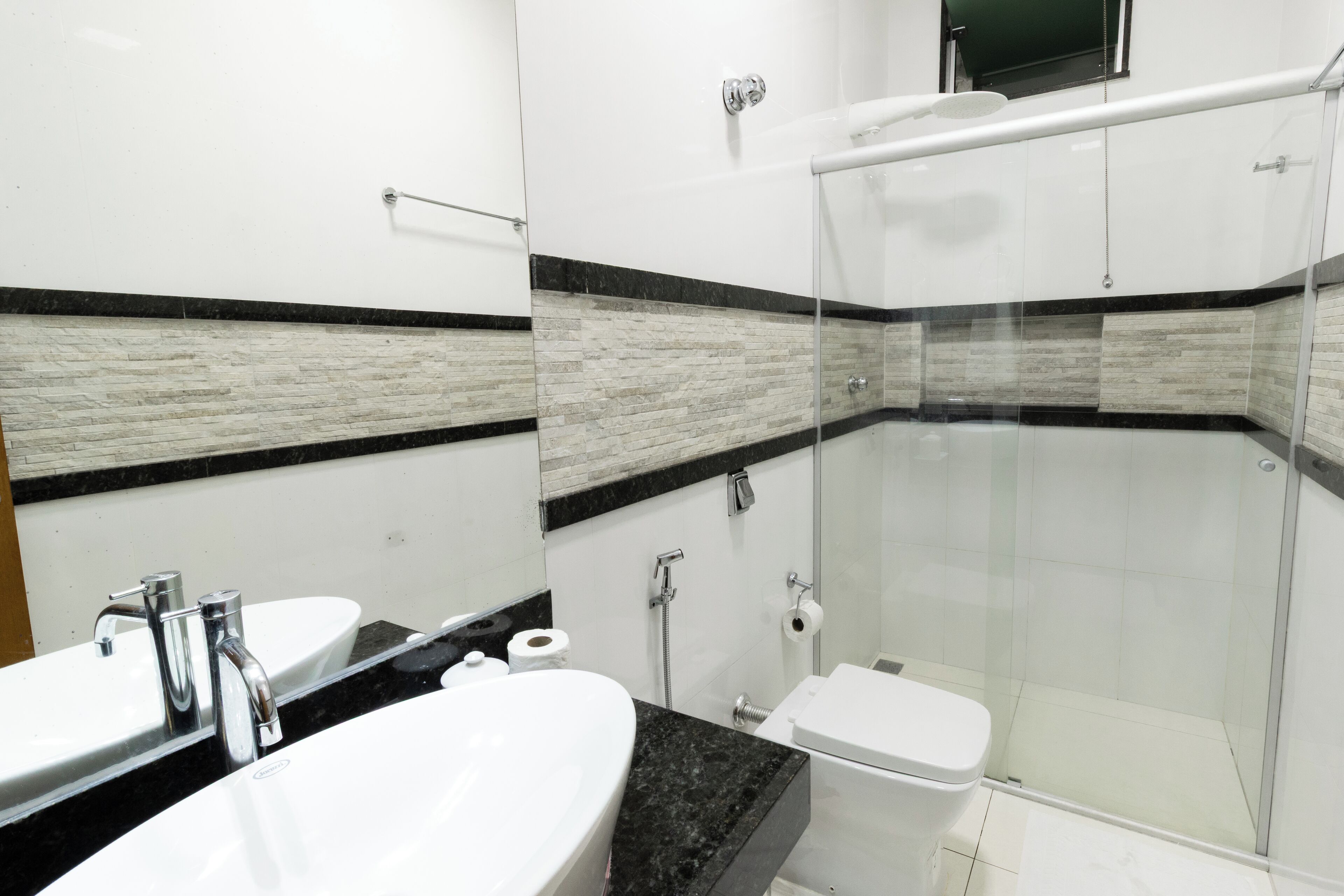 A modern bathroom with a glass-enclosed shower, a white sink, and a toilet.
