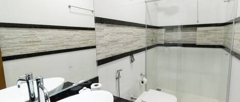 Een moderne badkamer met een douchecabine van glas, een wit wastafelmeubel en een toilet.