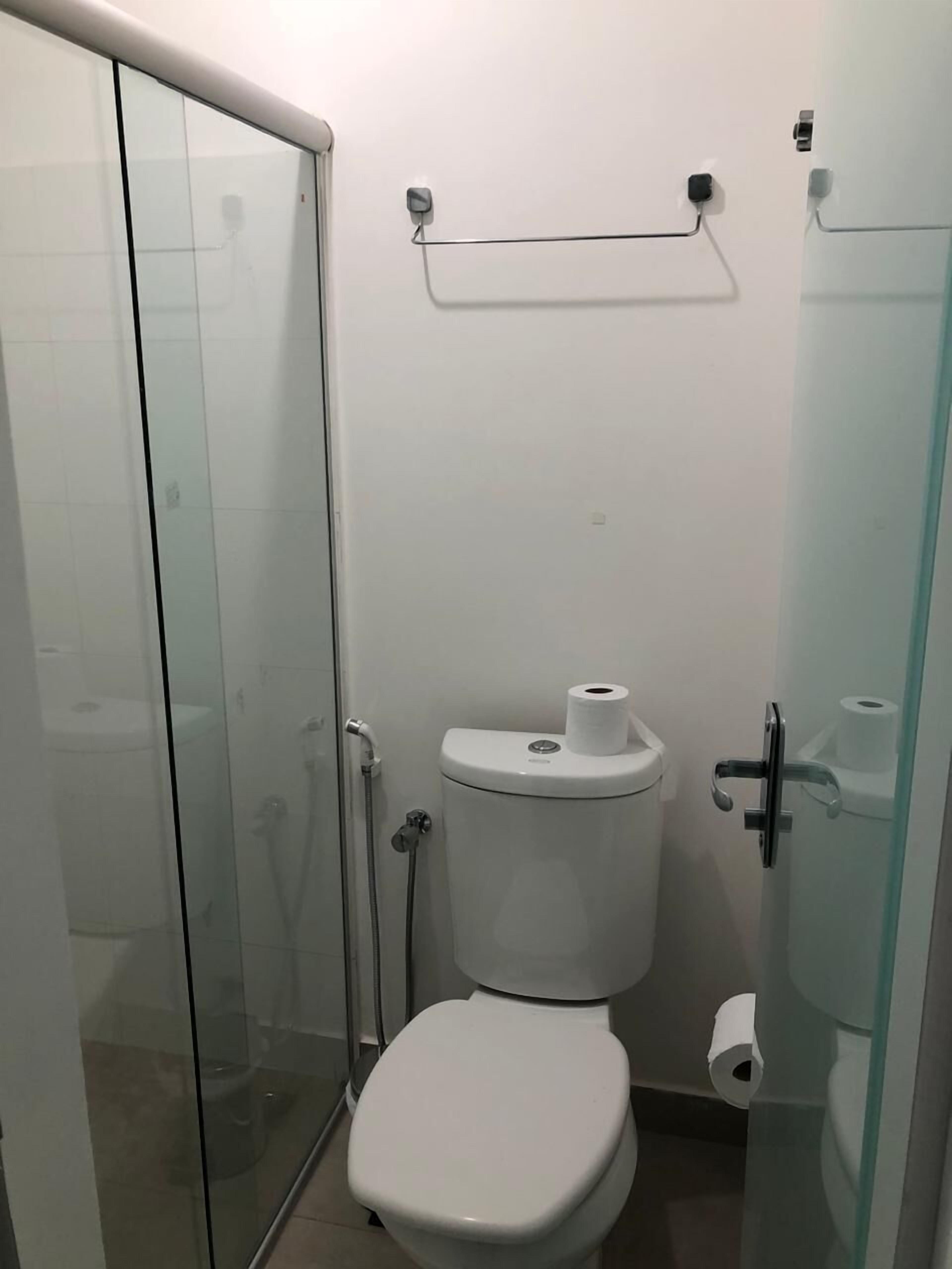 A small, modern bathroom with a glass shower enclosure, a toilet, and a glass partition.