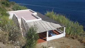 En byggnad vid kusten med en takterrass, en liten pool och utsikt över havet.