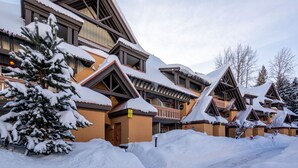 A snow-covered lodge with multiple buildings, a snow-covered tree, and a clear sky.