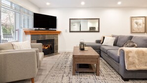 A living room with a fireplace, a flat-screen TV, a sofa, and a coffee table.