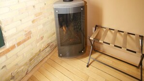 Une pièce avec un mur en briques, un plancher en bois et un poêle à bois.