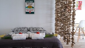 Ein ordentlich bezogenes Bett mit einem schwarz-weißen Blumendekor, zwei ordentlich gefaltete Handtücher und ein dekoratives Wandbild.