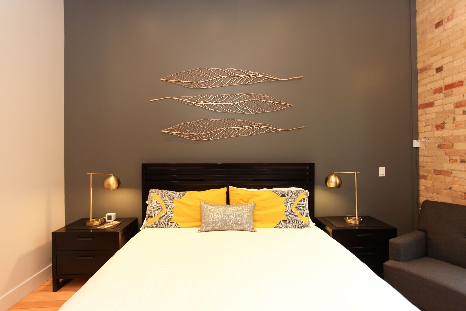 Quarto com cabeceira de madeira escura, colcha branca e duas mesas de cabeceira com luminárias.