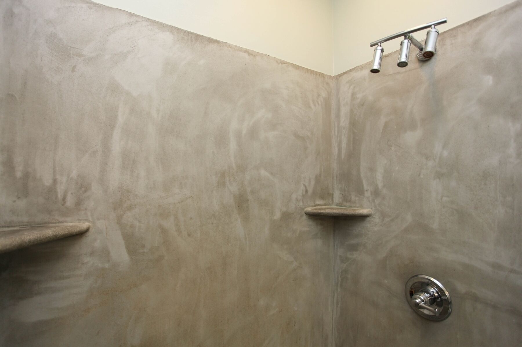 Ducha con pared curva, cabezal de ducha de mano y grifo de pared.