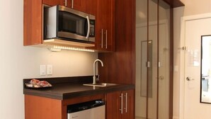 A compact kitchen with wooden cabinets, a built-in microwave, and a dishwasher. - Discover the cozy Napoli Suite in the heart of downtown Saugatuck, a charming retreat for two. (Saugatuck)