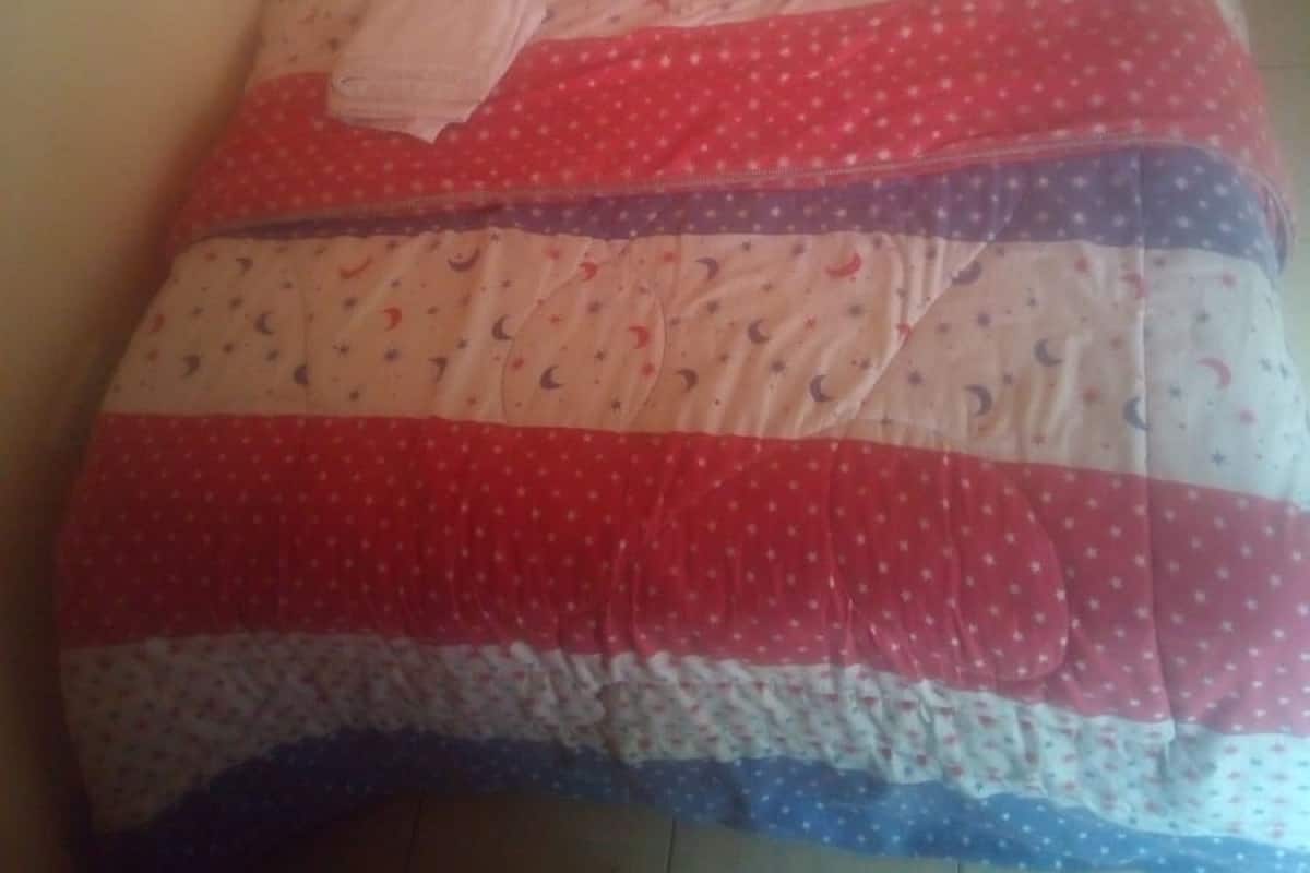 A bed with a quilted blanket featuring a pattern of stars and crescent moons.