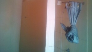 A bathroom with a shower, a towel hanging on a rack, and a visible light switch on the wall. - Desai Annex Guest House (Nairobi)