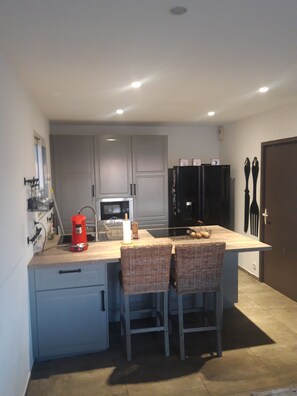 A compact kitchen with a central island, grey cabinets, and a black refrigerator. - VILLA IN CAMARGUE, 6KM FROM THE SANDY BEACHES, ABOVE GROUND POOL and BAR (Salin de Giraud)