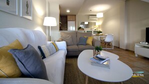 A modern living room with a sofa, a coffee table, and a dining area in the background. - Apartamento del Cabo I (Ventorros de San José)