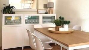 A modern kitchen with white cabinetry, a wooden dining table, and a hanging light fixture. - Apartamento del Cabo I (Ventorros de San José)