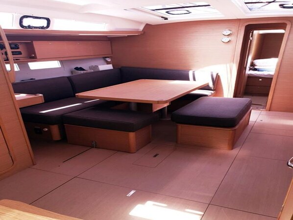 Un intérieur compact comprenant une table et des bancs en bois, un petit coin cuisine et un espace nuit réduit.