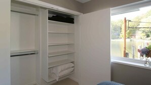 Une chambre dotée d’un placard intégré, d’une fenêtre donnant sur un plan d’eau et d’un lit.