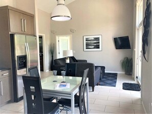 A compact living space with a dining area, kitchenette, and a flat-screen TV mounted on the wall.