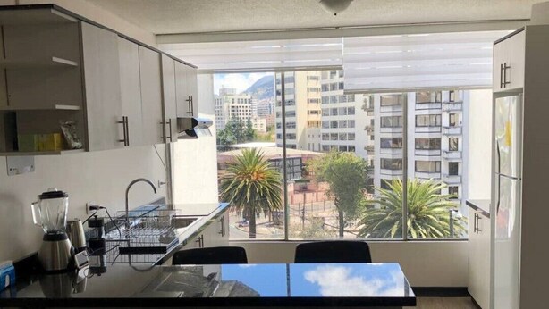 A modern kitchen with a large window, a built-in island, and a view of a cityscape. - Excellent location and comfort near La Carolina Metro Station (Quito)