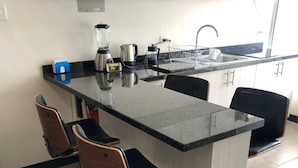 A kitchen with a central island, bar stools, a blender, a kettle, and a coffee maker. - Excellent location and comfort near La Carolina Metro Station (Quito)