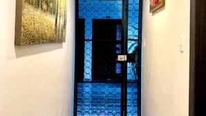A hallway with a wooden floor, a black door with a blue circular pattern, and a painting on the wall. - Excellent location and comfort near La Carolina Metro Station (Quito)