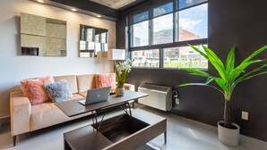 A modern living room with a sofa, a coffee table, a laptop, and a potted plant. - Eclectic Loft with All Amenities (Montréal)