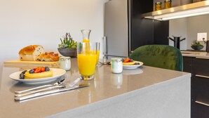 A breakfast setup with a plate of pancakes topped with fruit, a glass of orange juice, and a bowl of cereal. - Eclectic Loft with All Amenities (Montréal)