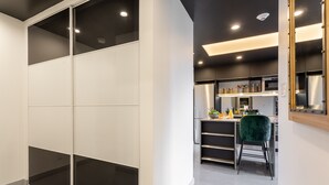 A modern kitchen with a dining area, featuring a green chair, a countertop with kitchen appliances, and a sliding door closet. - Eclectic Loft with All Amenities (Montréal)