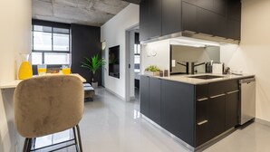 A modern kitchen with dark cabinetry, a stainless steel sink, and a built-in oven. - Ambient Loft with All Amenities (Montréal)