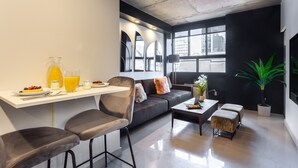 A modern living space with a sofa, coffee table, and dining area with breakfast items. - Ambient Loft with All Amenities (Montréal)