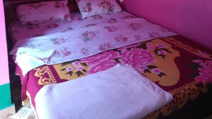 Un lit avec une literie à motifs floraux, une moustiquaire et un tapis à motifs.