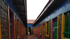Un couloir aux murs de briques et aux cadres de fenêtres colorés, qui mène à une porte portant l’inscription « Cesar Repubic ».