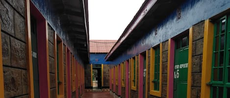 A corridor with brick walls and colorful window frames, leading to a door marked "Cesar Repubic".