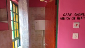 Une salle de bain équipée de toilettes, d’un lavabo, d’une douche et d’un distributeur de papier toilette fixé au mur.