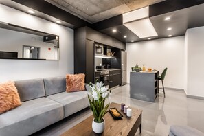 Una sala de estar moderna con un sofá gris, una mesa de centro de madera y un jarrón con flores blancas.