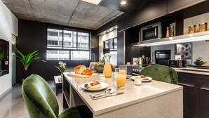A modern kitchen with a central island, dark cabinetry, and a large window providing natural light.