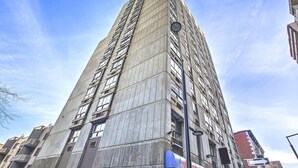 Un immeuble moderne et imposant, doté d’une façade à motifs géométriques et d’une entrée d’angle bien visible.