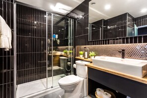 Contemporary bathroom with sleek shower enclosure, white toilet, and large sink.