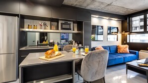 Une cuisine moderne avec un coin repas, un canapé bleu et un ordinateur portable posé sur une table.