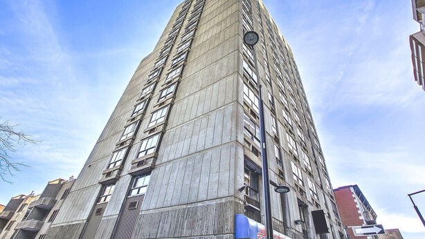 A tall, modern building with a grid of windows and a prominent corner entrance. - Modern Loft near McGill University (Montréal)