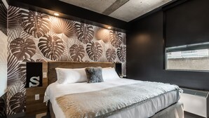 A modern bedroom with a large bed, a wooden headboard, and a wall with a leaf pattern. - Modern Loft near McGill University (Montréal)