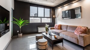 A modern living room with a sofa, coffee table, and potted plant. - Modern Loft near McGill University (Montréal)