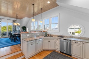 A kitchen with white cabinets, a granite countertop, a dishwasher, and a large window.