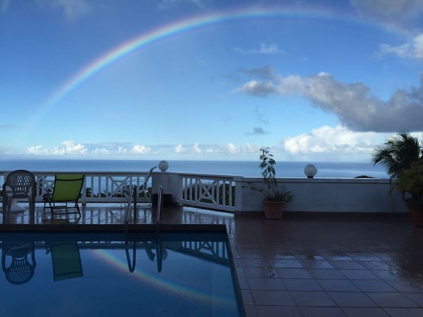 Ein Pool auf dem Dach mit Blick auf den Ozean und einem Regenbogen.