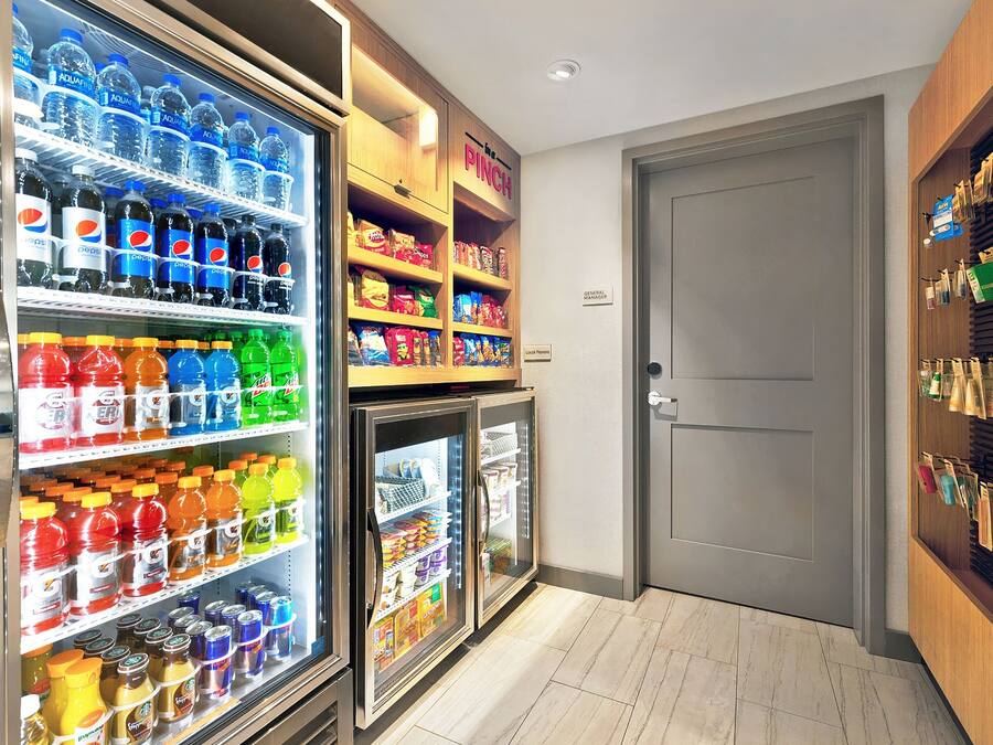 A hotel room with a minibar, a refrigerator stocked with beverages and snacks, and a door to the right.