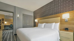 A hotel room with a large bed, a desk, and a chair.
