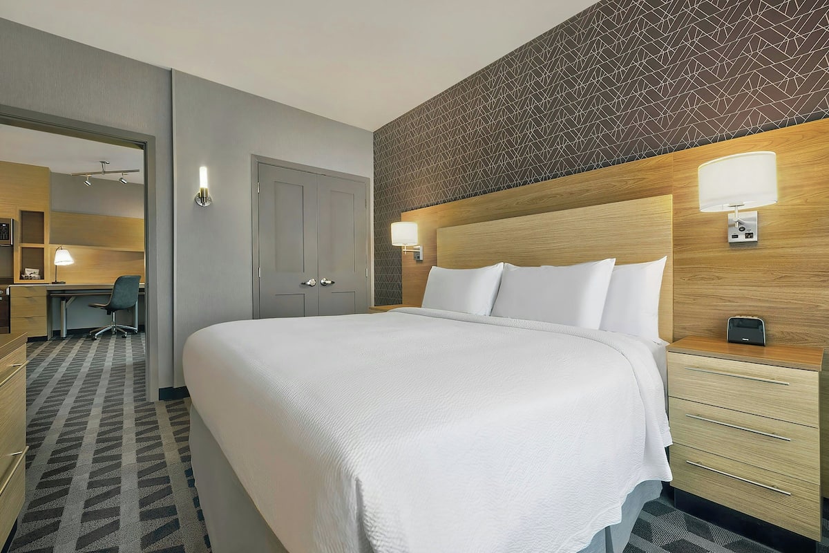 A hotel room with a large bed, a desk, and a chair.