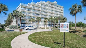 Un hôtel à plusieurs étages, doté d’une façade blanche, de balcons et de palmiers en premier plan.