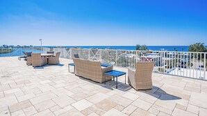 Une terrasse sur le toit, aménagée avec des meubles en osier et offrant une vue sur la mer.