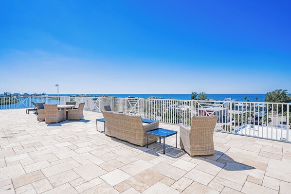 Terraza en la azotea con mobiliario de mimbre y vistas al mar.